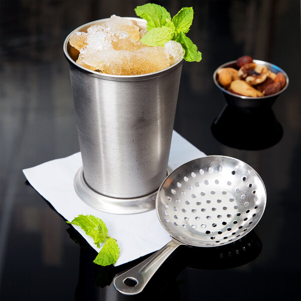 An American Metalcraft stainless steel cup with ice and mint leaves on a black surface.