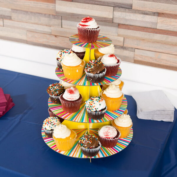 A Wilton neon striped disposable cupcake stand with a variety of cupcakes on it.