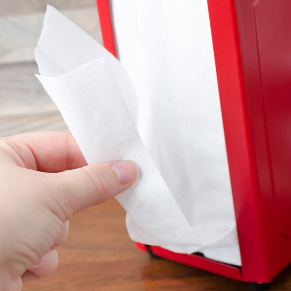 A hand holding a white Choice Tall-Fold dispenser napkin.