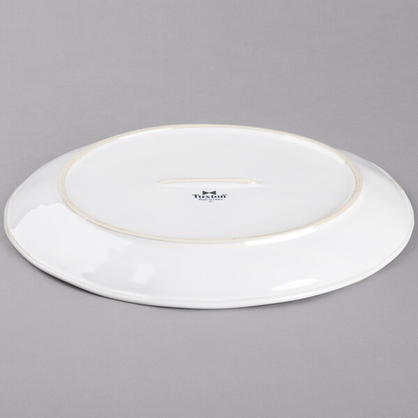 A white Tuxton china platter with a gold rim.