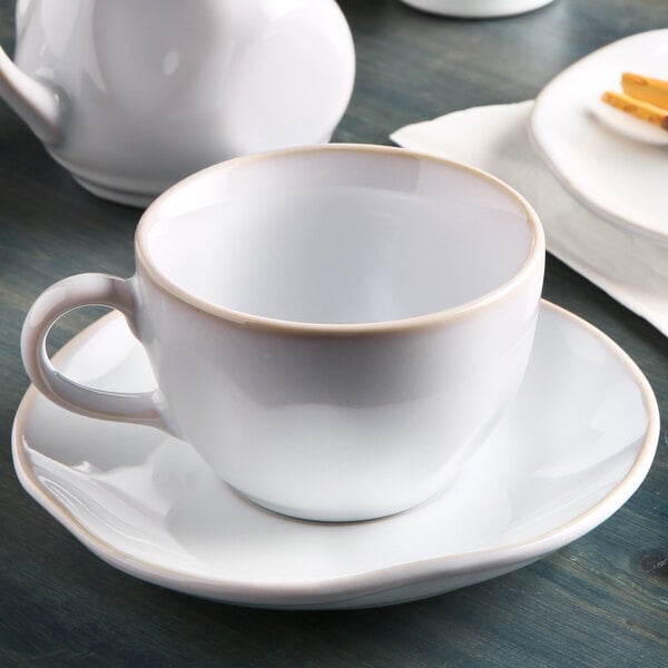 A Tuxton Artisan Agave white china cup and saucer on a table.