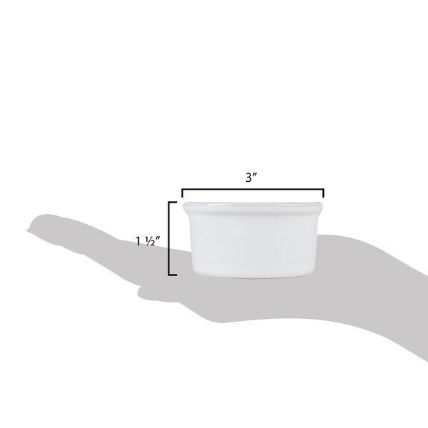 A hand holding a white Tuxton China ramekin with a shadow.