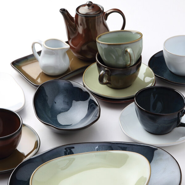 A Tuxton TuxTrendz Artisan Agave saucer on a table with a white cup.