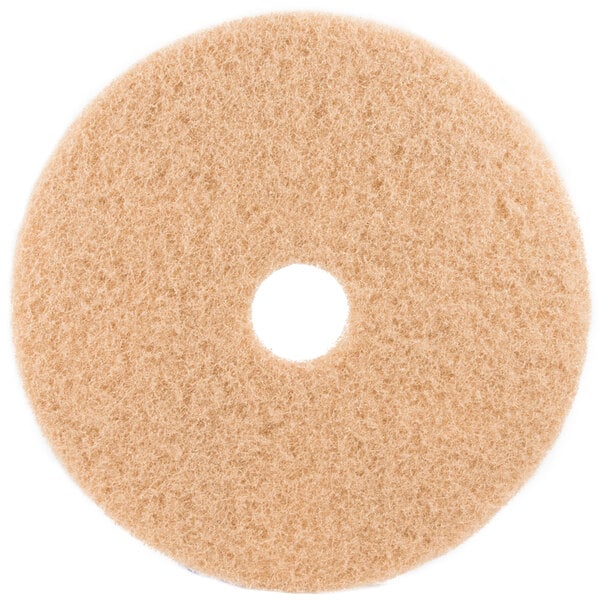 A 3M tan circular floor pad with a hole in the middle on a white background.