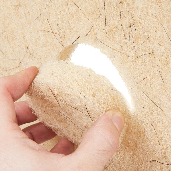 A hand holding a 3M tan burnishing floor pad with a hole in it.
