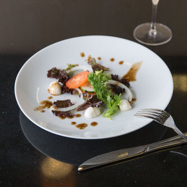 A plate of food with a fork and knife on a white Arcoroc porcelain plate.