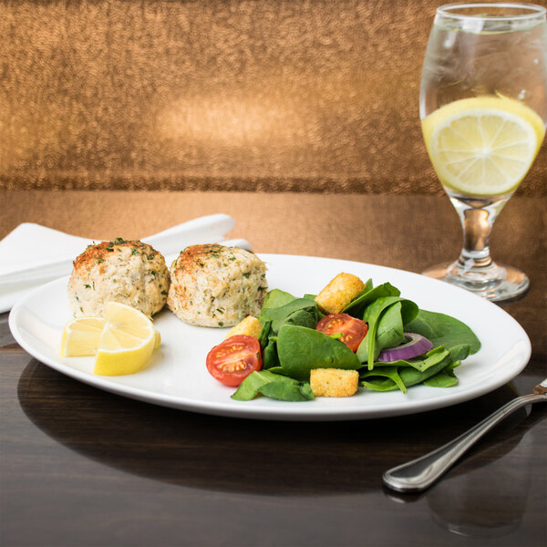 A plate of food on a table with a glass of water and a lemon slice.