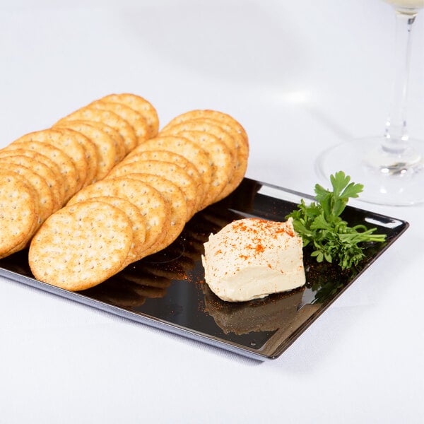 A WNA Comet black rectangular tray with crackers and cheese and a glass of wine on a white tablecloth.