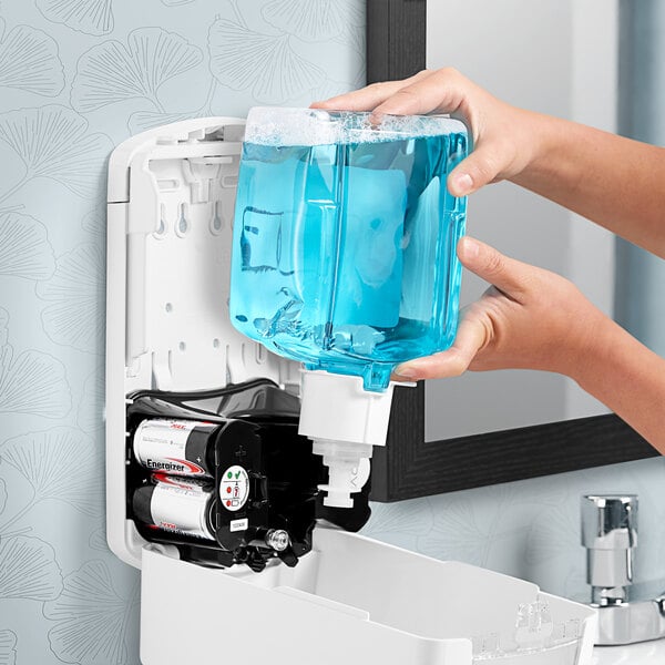 A person using GOJO foaming hand soap in a dispenser to wash their hands.