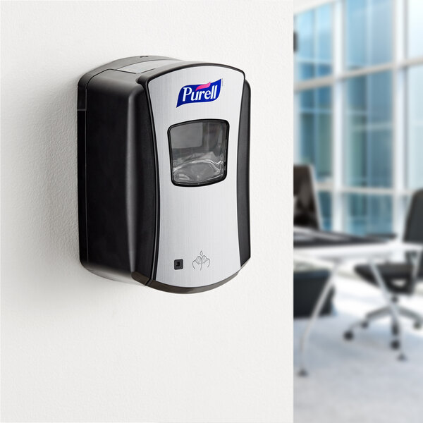 A black Purell touchless hand sanitizer dispenser on a wall.