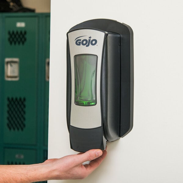 A person using a GOJO chrome manual soap dispenser.