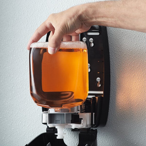 A hand using GOJO FMX Fresh Fruit foaming hand soap in a dispenser.