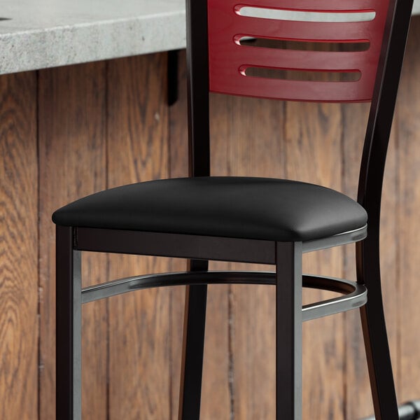 A Lancaster Table & Seating black vinyl padded seat on a metal frame.