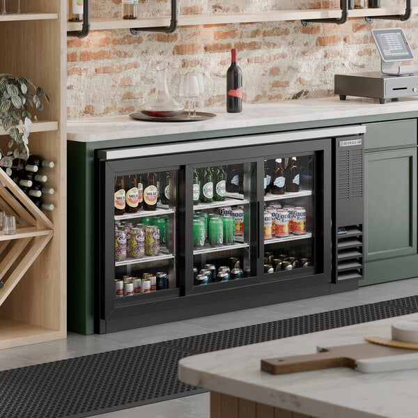 A black counter height glass door pass through back bar refrigerator filled with assorted beverages.