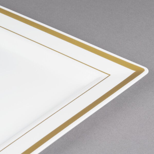 A Fineline Silver Splendor ivory plastic square plate with gold bands on a table.