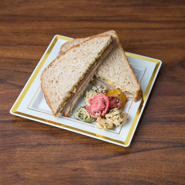 A Fineline Silver Splendor plastic square plate with a sandwich on it, with a side of vegetables.