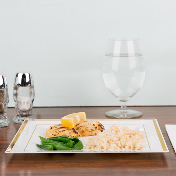 A Fineline ivory plastic square plate with gold bands holding rice, chicken, and vegetables with a lemon wedge on top.