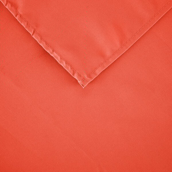 A close-up of an orange rectangular cloth table cover with hemmed edges.
