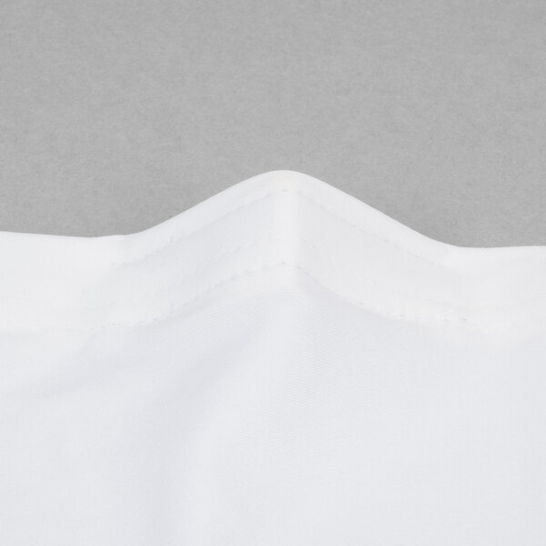 A close up of a white spandex table cover with a folded edge.