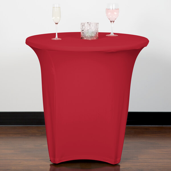 A table with a Snap Drape crimson spandex table cover and two wine glasses on it.