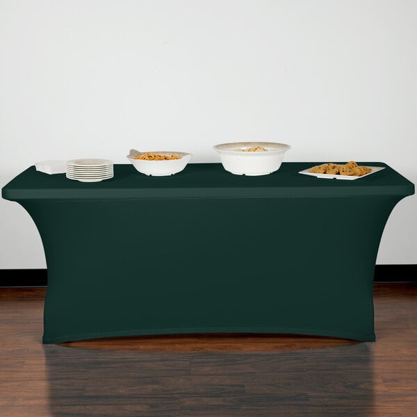 A table with a Snap Drape hunter green spandex table cover and bowls of food on it.