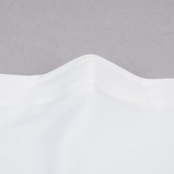 A close up of a white spandex table cover with a folded edge.
