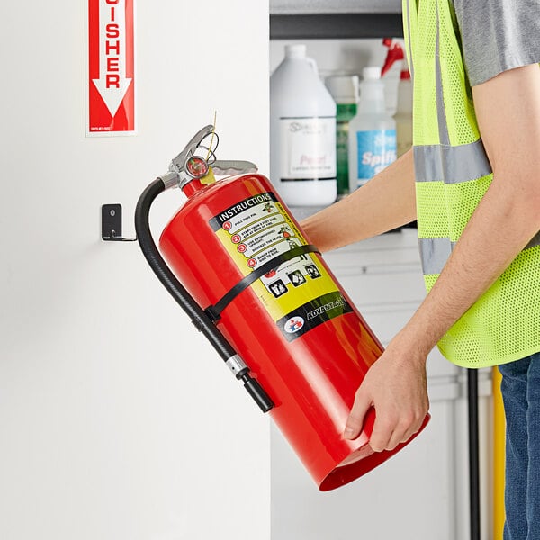 A man in a safety vest holding a Badger Advantage fire extinguisher.