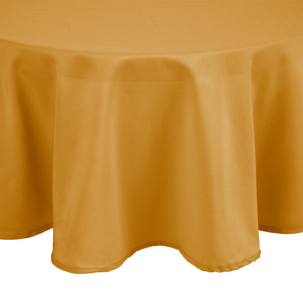 A round table with a yellow tablecloth on it.