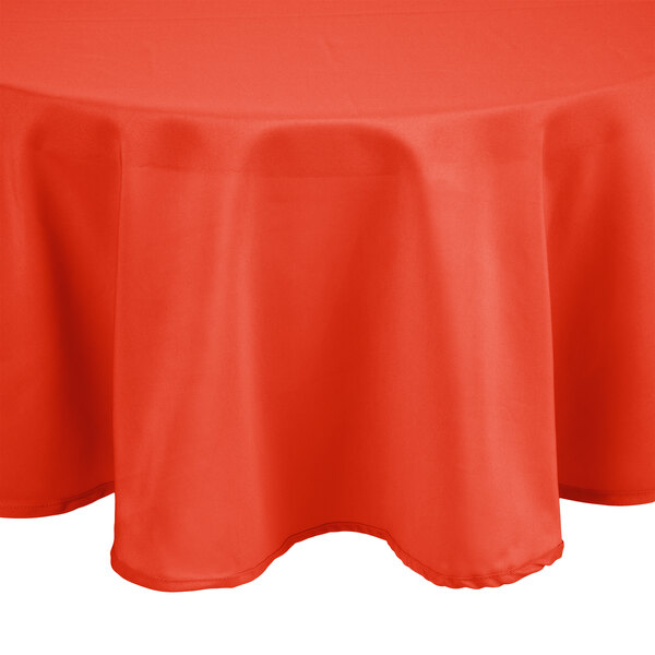 An Intedge orange 100% polyester round tablecloth on a table.
