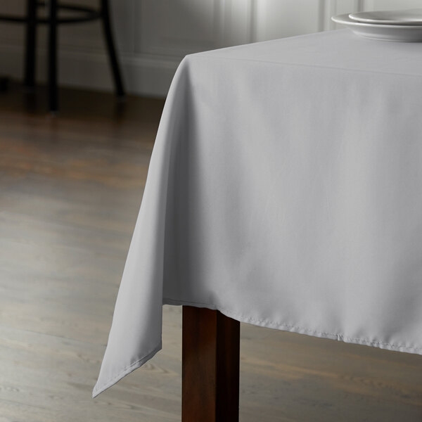 A table with a gray Intedge square table cloth.