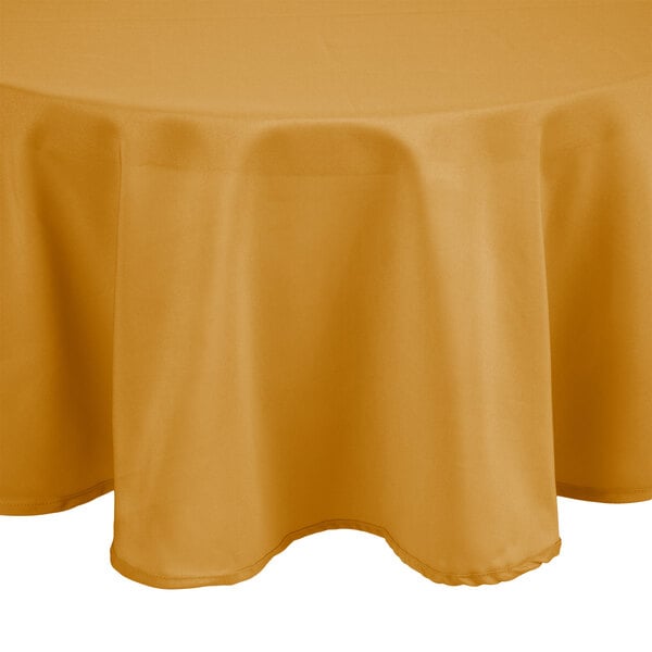 A round table with a gold Intedge tablecloth on top.