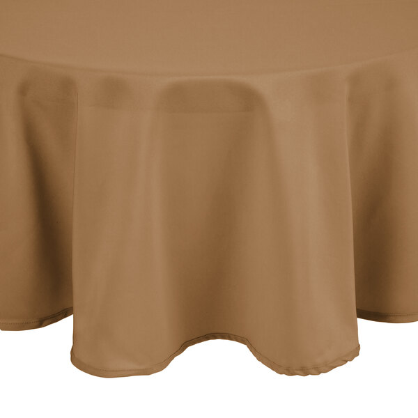 An Intedge beige round cloth table cover on a table.