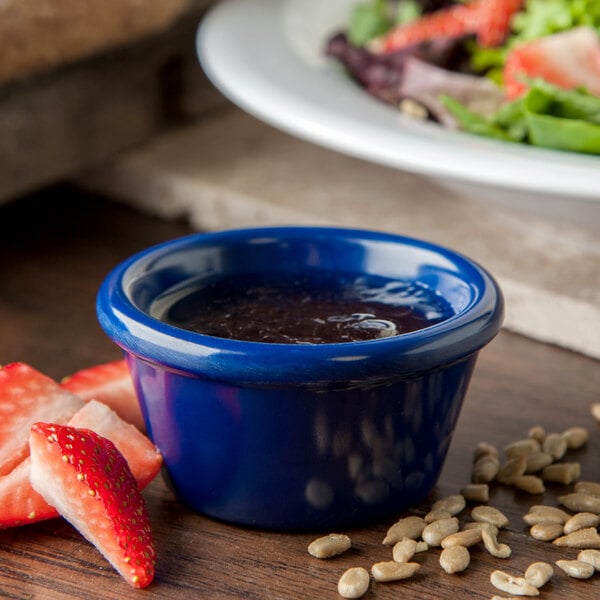 A blue Carlisle ramekin filled with liquid next to a salad.
