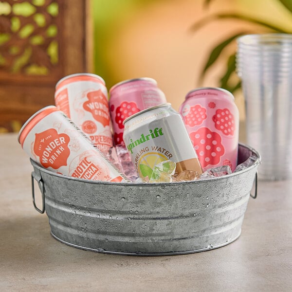 An American Metalcraft galvanized metal tub filled with ice, water, cans of soda and plastic cups on an outdoor patio table.