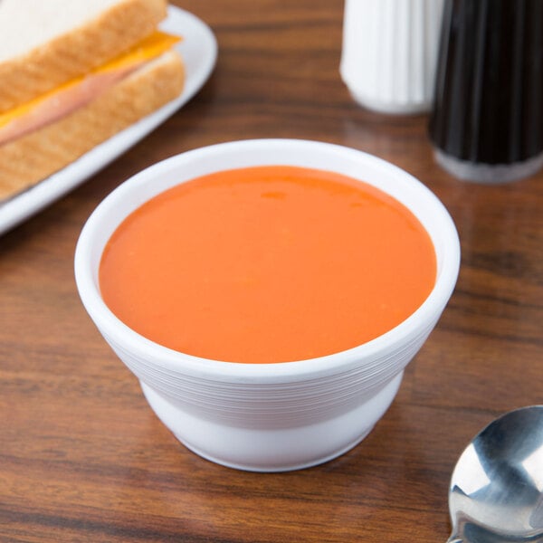 A white Minski melamine bowl filled with soup on a table.