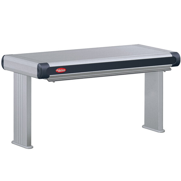 A grey rectangular Hatco strip warmer with a black handle over a stainless steel table.