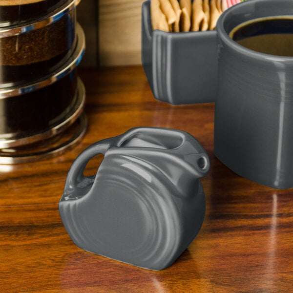 A grey ceramic Fiesta® Mini Disc Creamer Pitcher on a table.