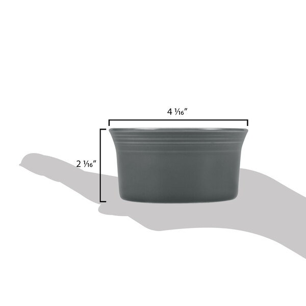 A hand using a grey Fiesta china ramekin to measure ingredients.