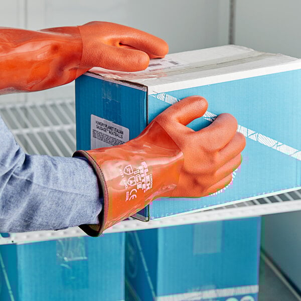 A person wearing red Cordova Freezer gloves opening a box.