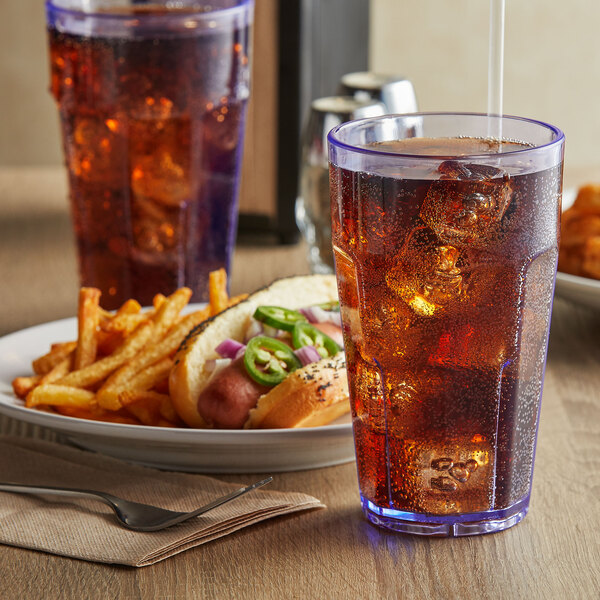 A blue GET plastic tumbler filled with soda and ice next to a plate of food.