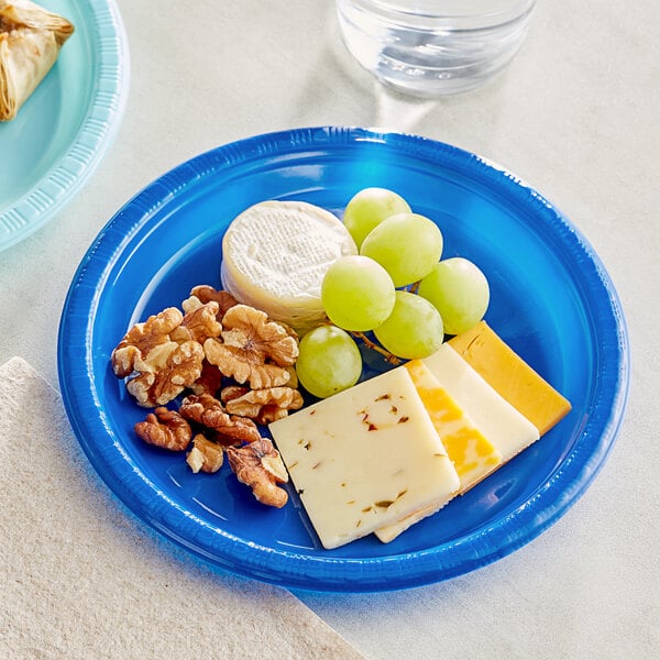 A Creative Converting cobalt blue plastic plate with cheese, grapes and walnuts.