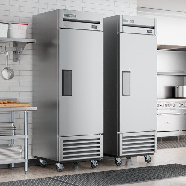 Two True T-23-HC stainless steel reach-in refrigerators in a kitchen.