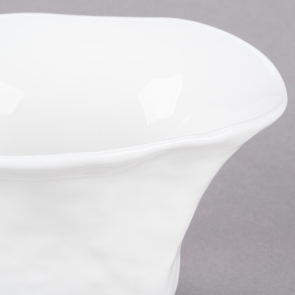 A close-up of a white 10 Strawberry Street porcelain bowl with a wavy design on it.