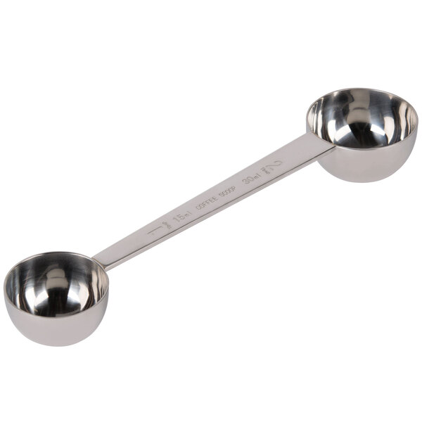 A stainless steel measuring spoon with a handle sitting in a round bowl.
