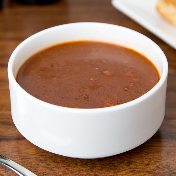 A 10 Strawberry Street white bone china bouillon bowl filled with red soup on a table.