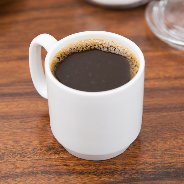 A 10 Strawberry Street Izabel Lam Pond white bone china espresso cup and saucer with a cup of coffee on a table.