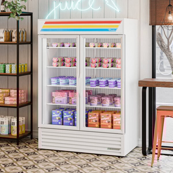 A white glass door merchandiser freezer with LED lighting, stocked with various frozen products.