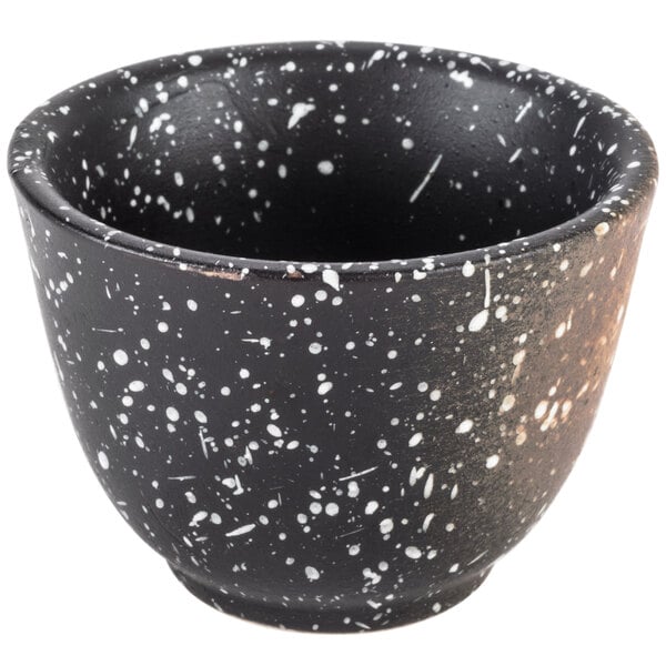 A white speckled stoneware sake cup with a black and white speckled design.