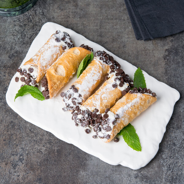 A rectangular white porcelain platter with textured edges holding a pastry.