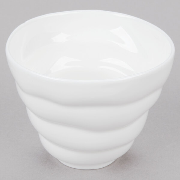 A close-up of a 10 Strawberry Street Bright White Porcelain Sorbet Cup with a white swirl pattern on a gray surface.